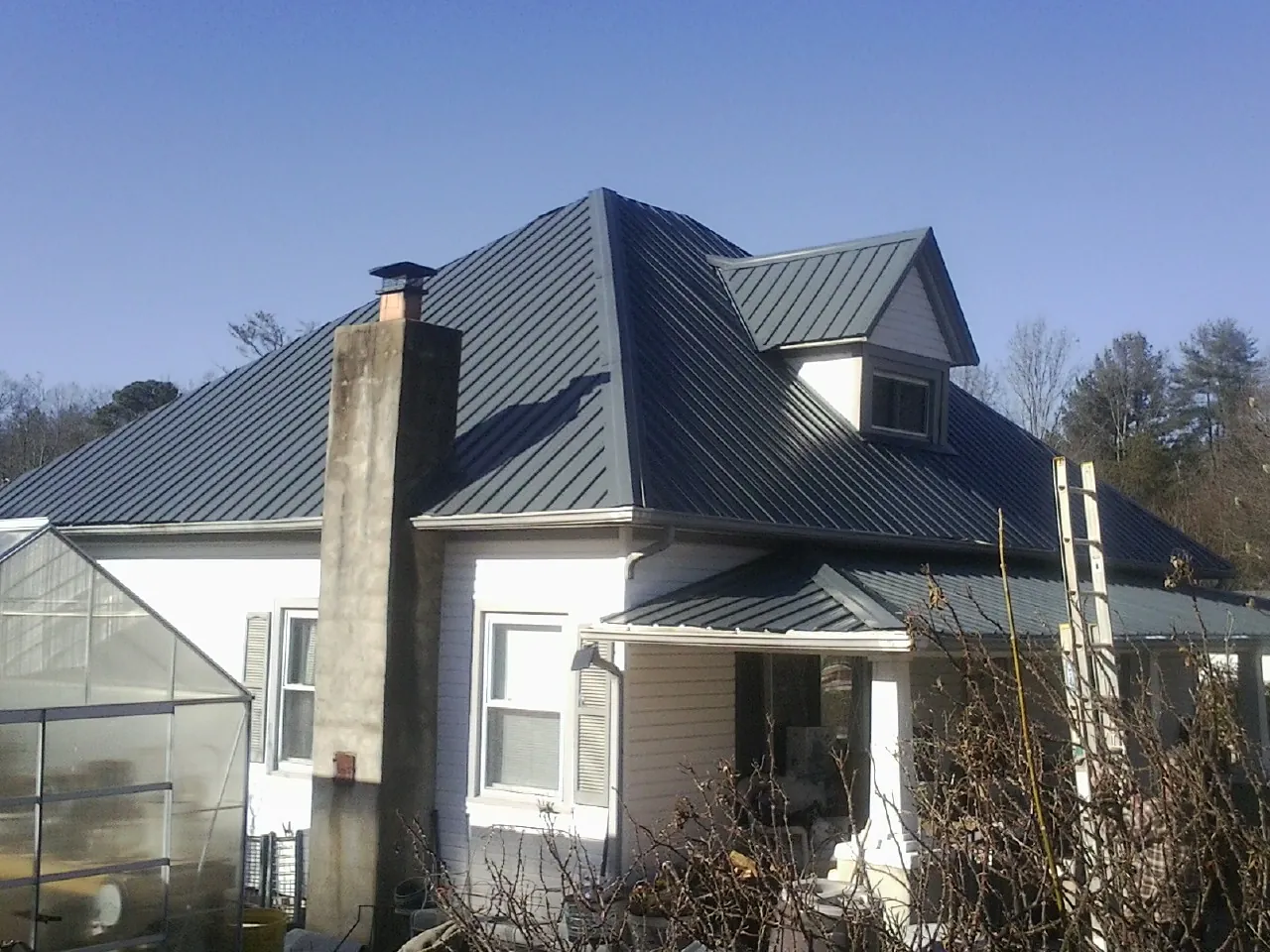 Dark blue standing seam metal roof on a white farmhouse with dormer — Slate & Tile Roof Repair by Roofing Brothers in Deary