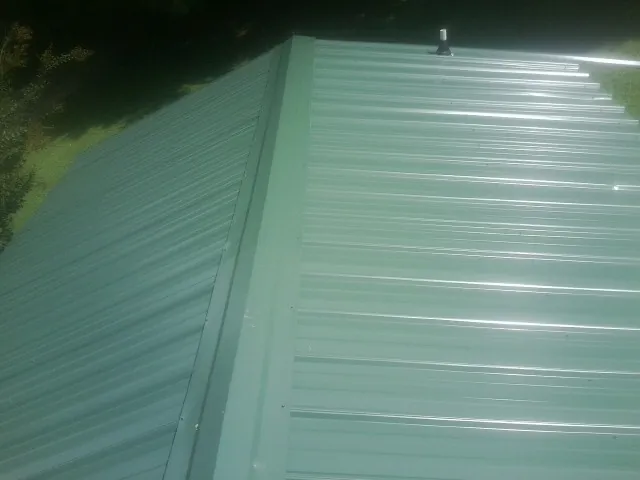 New green metal panels meeting at the ridge of a roof — Flat Roof Repair work by our crew in Deary