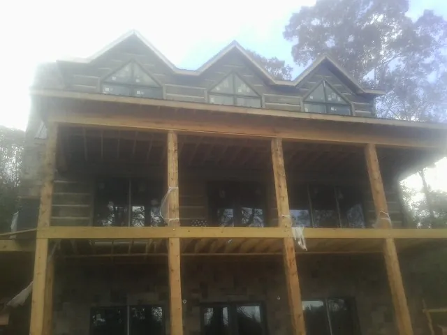 Dormers and porch framing on a large log home under construction — Roof Coating work by our crew in Deary