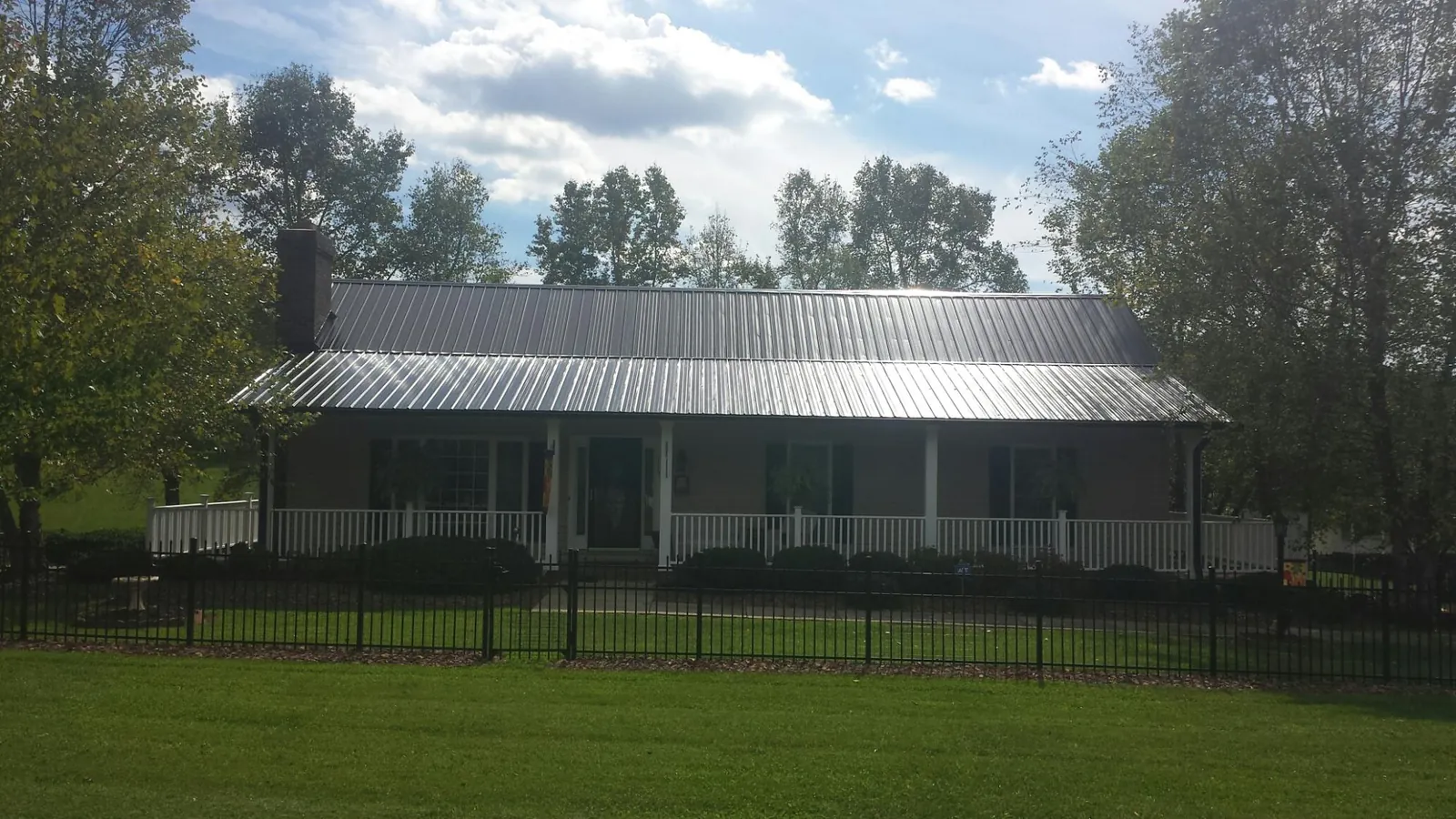 Gray metal roof on a brick ranch with a full width front porch — Gutter Guard Installation work by our crew in Deary
