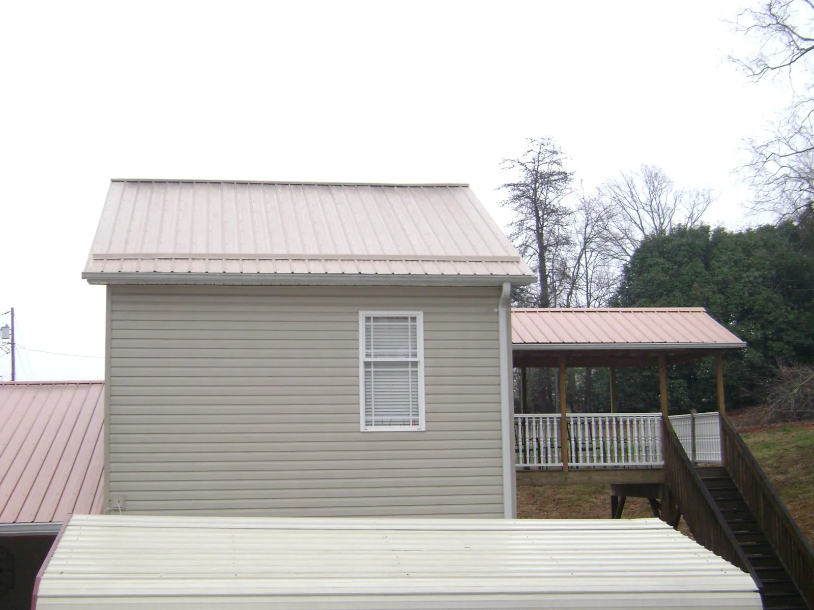 Tan metal roofs on a two story addition and attached porch, from a Roof Replacement job in Deary