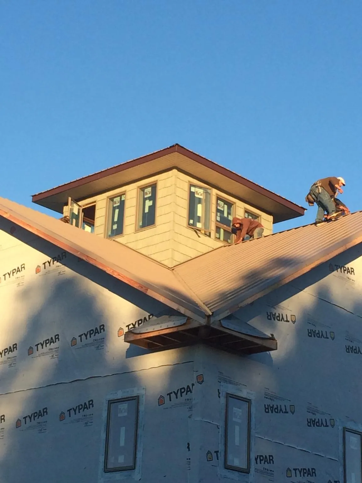 Roofers working around a rooftop cupola on a new metal roof at sunset — Roof Waterproofing in Deary by Roofing Brothers